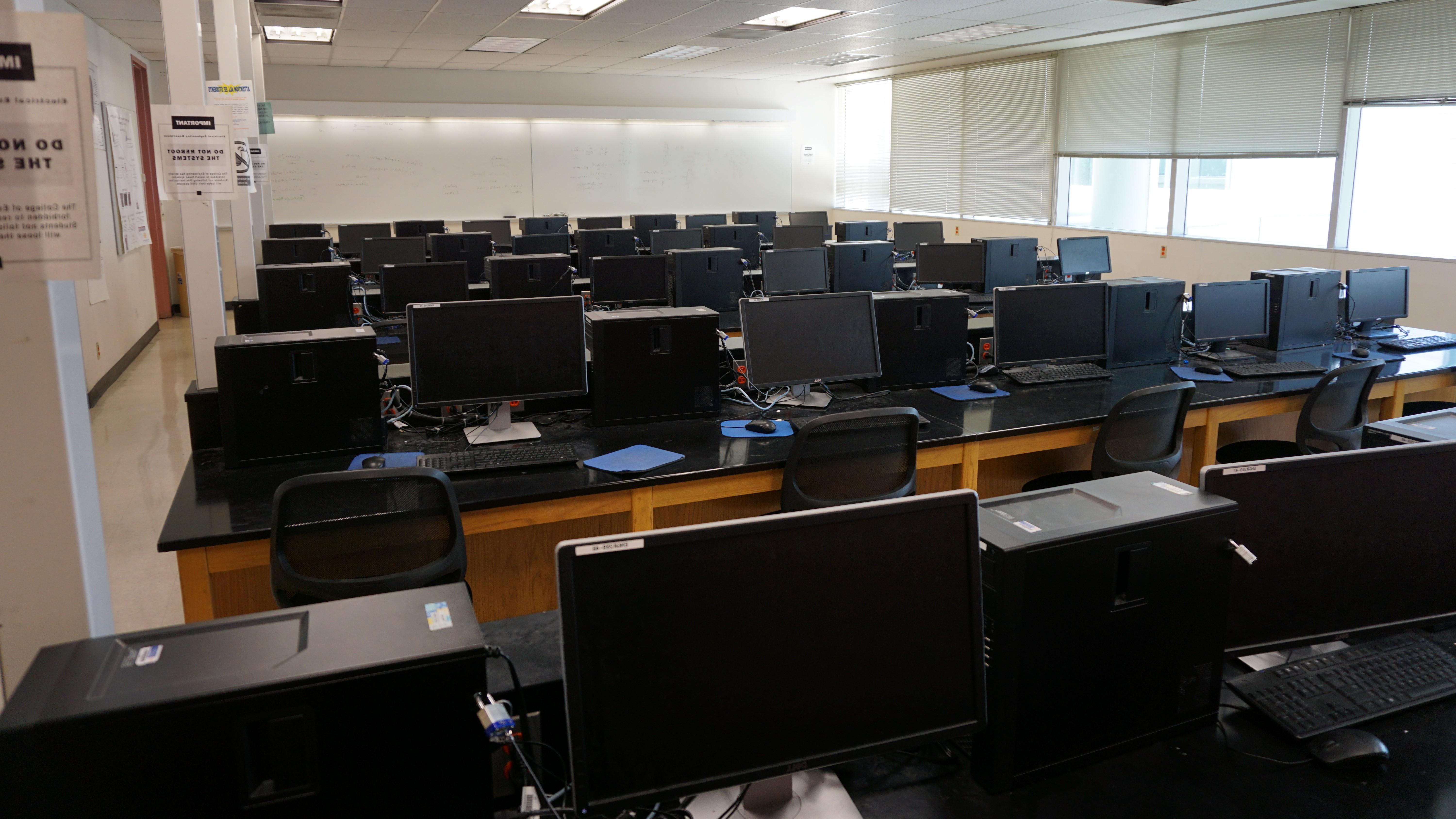 A classroom with multiple rows of computers and monitors.