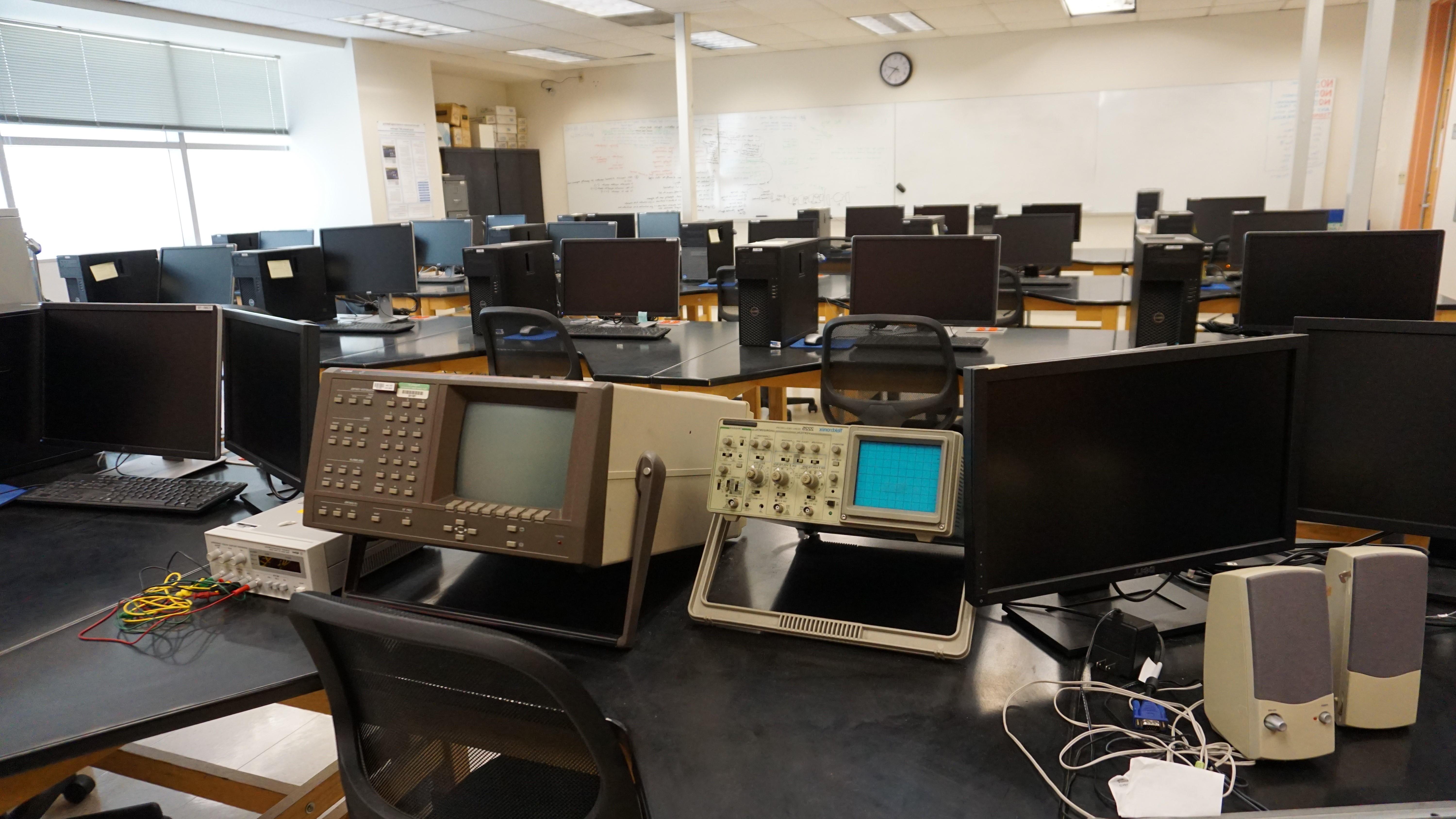 Rows of black monitors and a small bright blue screen on one of the lab machines.