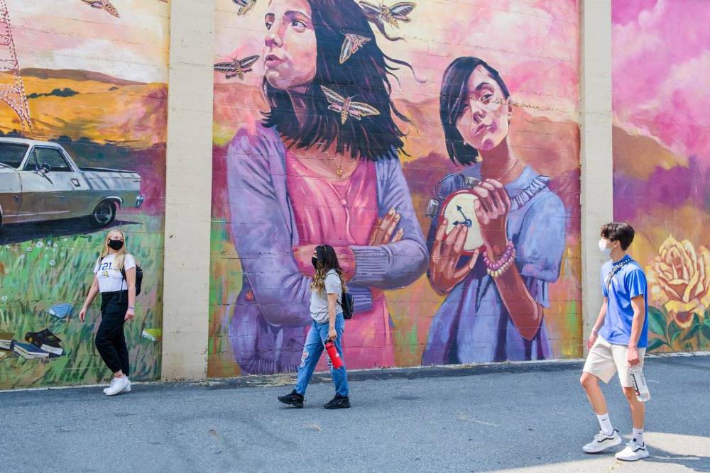 学生们在市中心的彩色壁画前漫步.